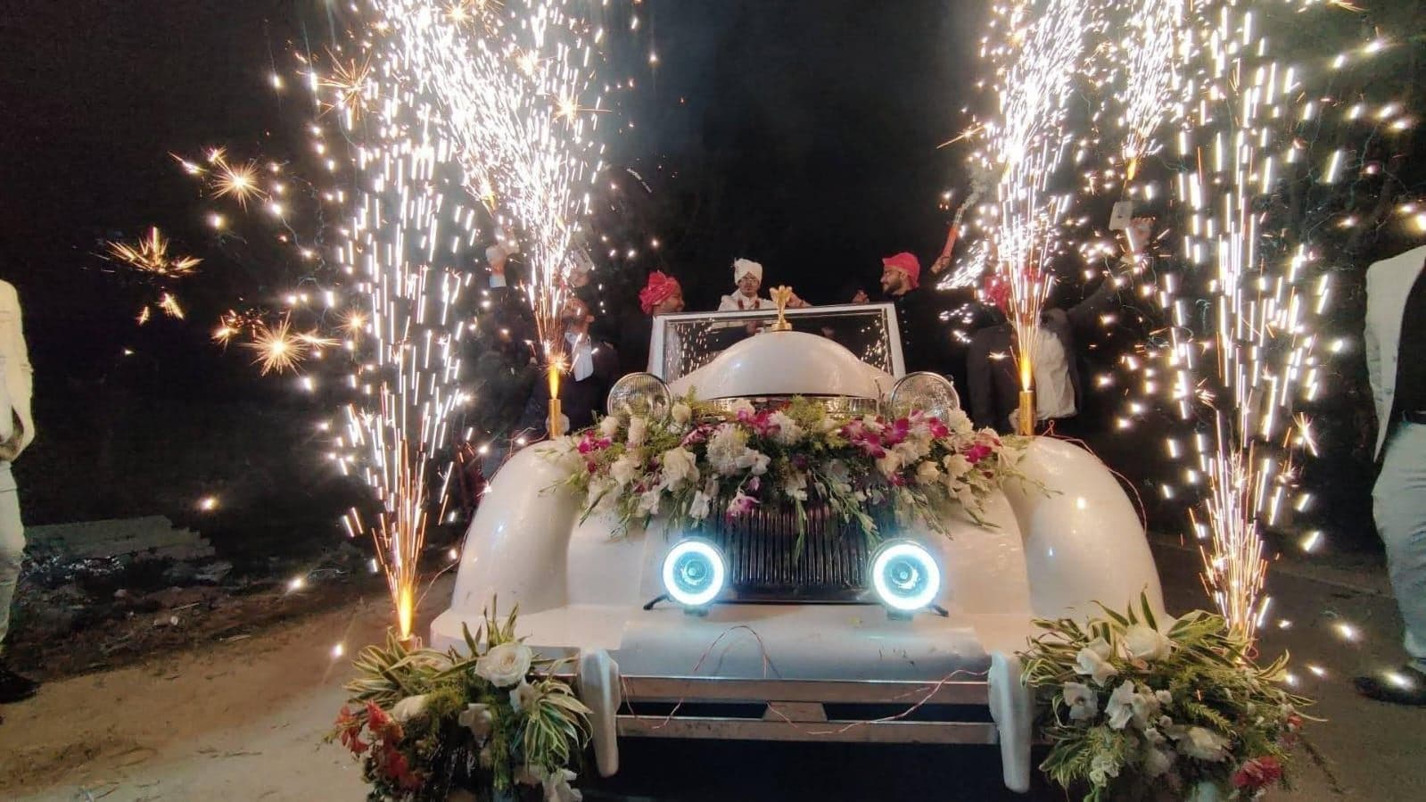 Cold pyro fountains lighting up a decorated wedding entry car at night in Siliguri