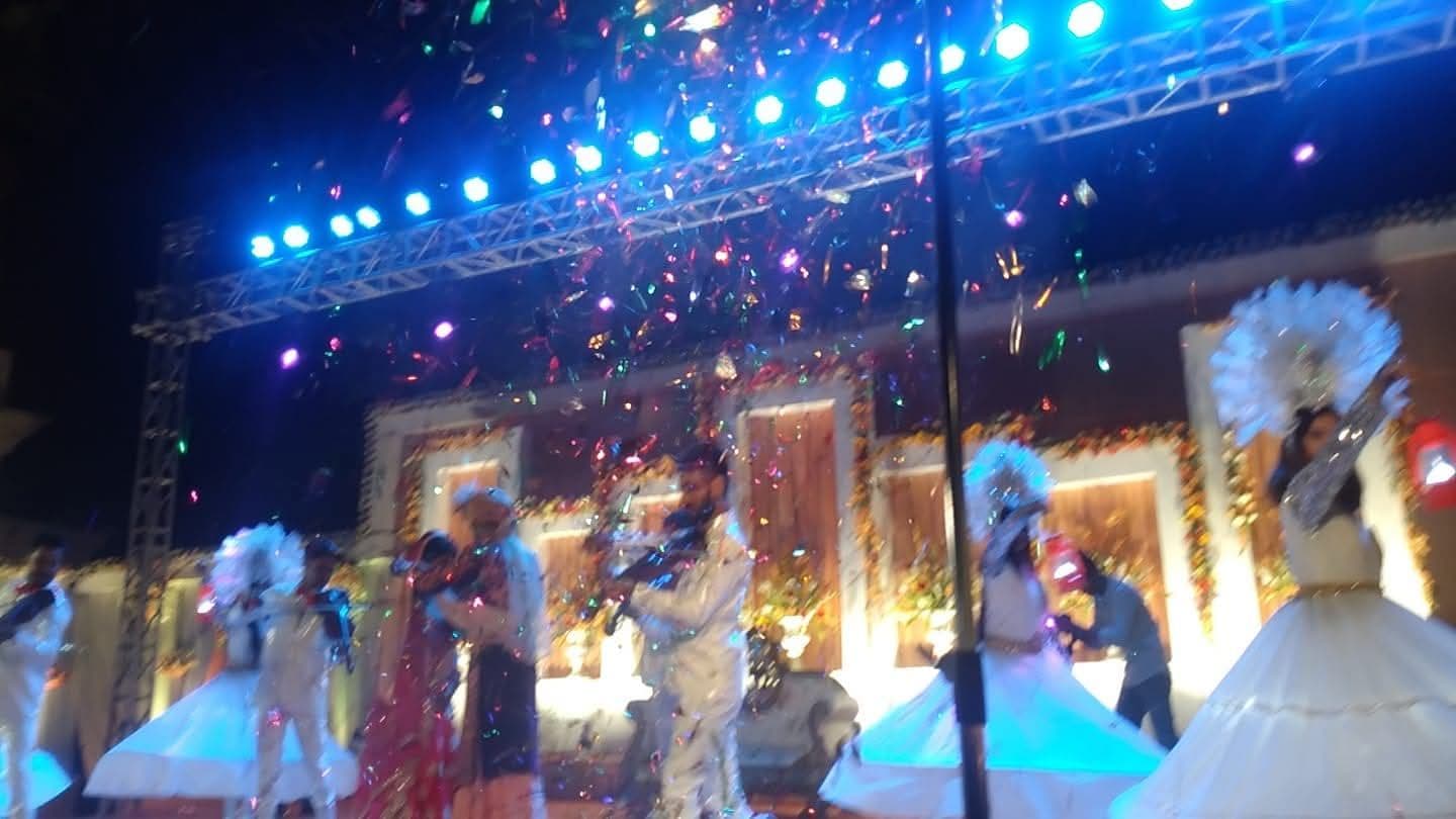 Confetti blast over a stage performance under blue lights