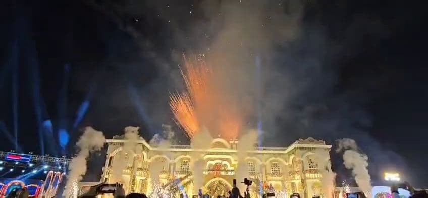 Fireworks bursting above a lit-up venue at night
